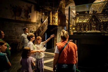Eine Gruppe von Kindern betrachtet im Aachener Dom den Marienschrein in einem Glaskasten.
