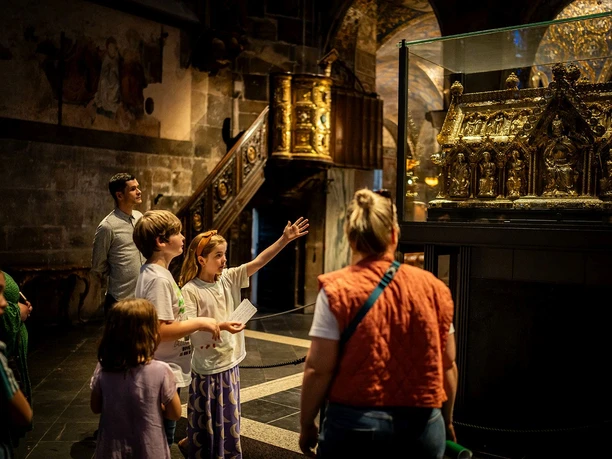 Eine Gruppe von Kindern betrachtet im Aachener Dom den Marienschrein in einem Glaskasten.