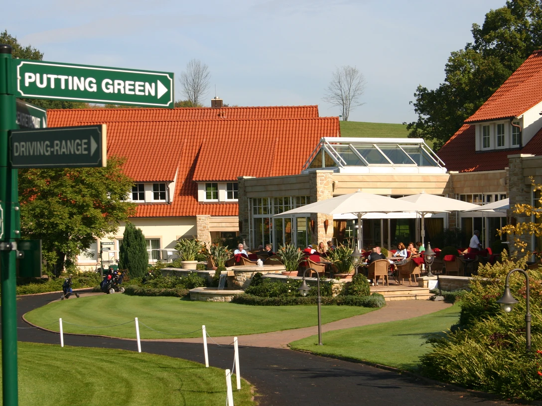 golfplatz_eggeberg_1_.jpg Ein Golfclub mit gepflegten Grünflächen, Sonnenschirmen und Hinweisschildern zur Driving-Range.