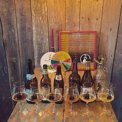 tasting Auf einem Holztisch stehen Flaschen verschiedener Biere nebeneinander und vor ihnen Gläser gefüllt mit jeweils einem Schluck Bier zum Probieren.