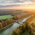 Mittellandkanal bei Bad Essen Luftaufnahme eines Kanals mit Brücke, umgeben von herbstlich gefärbten Bäumen bei Sonnenuntergang.