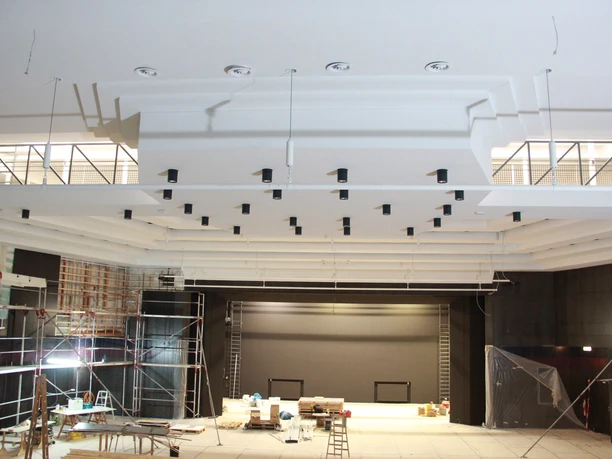 Innenansicht einer im Bau befindlichen Stadthalle mit modernem Bühnenbereich und Gerüsten.