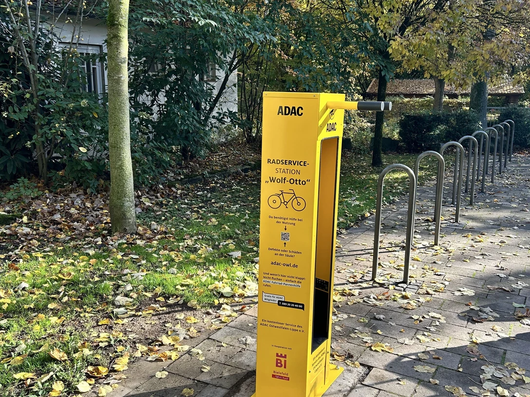 Radservicestation Bielefeld "Wolf-Otto" Gelbe Fahrradservice-Station von ADAC in herbstlicher Umgebung mit Bäumen und Laub auf dem Boden.