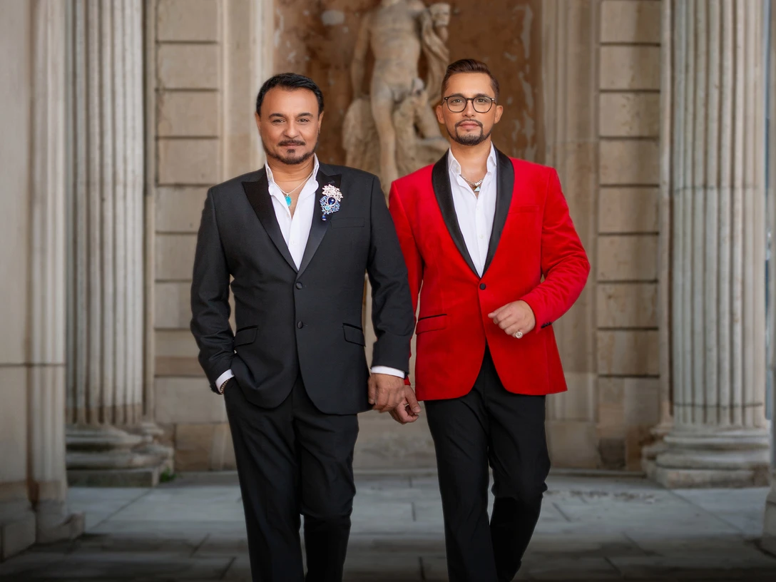 TENÖRE4YOU-2 Zwei Männer in eleganten Anzügen schreiten selbstbewusst durch einen Säulengang.