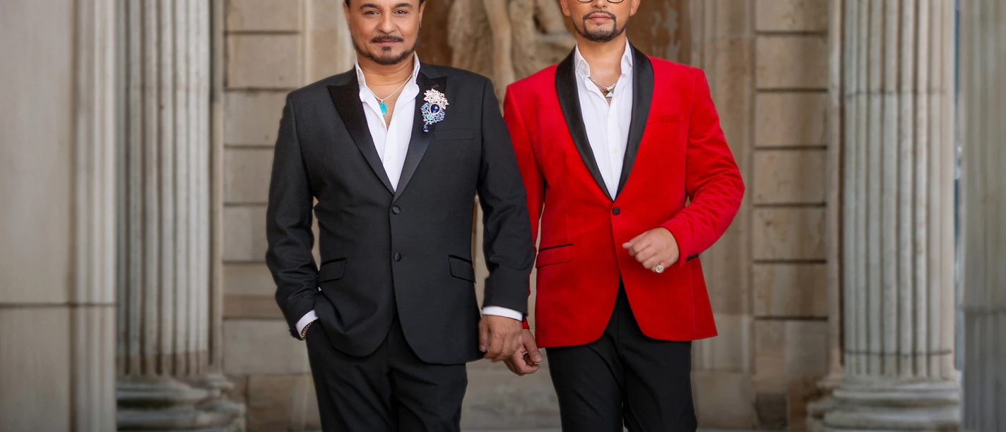 TENÖRE4YOU-2 Zwei Männer in eleganten Anzügen schreiten selbstbewusst durch einen Säulengang.