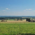 Weiter Blick über sanfte Hügel und Felder im Wiehengebirge, umgeben von verstreuten Bauernhöfen.