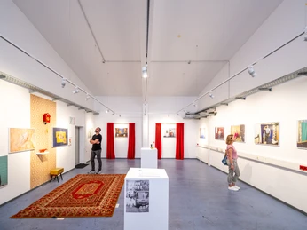 Bielefeld-Ostblock Kulturhaus-Teutoburger-Wald-D-Ketz-229.jpg Ein modernes Kunstmuseum mit hell erleuchteten Ausstellungsräumen und Besuchern, die Gemälde betrachten.