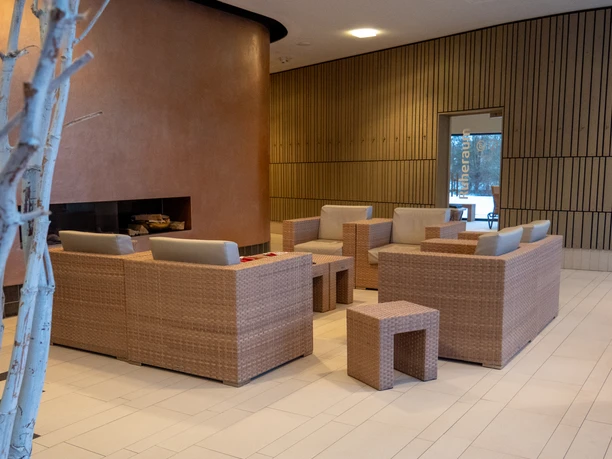 Vorraum des Saunabereichs mit Sesseln in warmen Farben und einer Tür zum Ruhebereich.