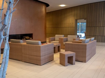 Sauna Foyer Vorraum des Saunabereichs mit Sesseln in warmen Farben und einer Tür zum Ruhebereich.