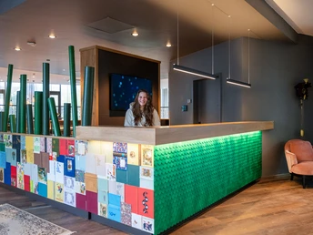 moderne und bunt gestaltete Rezeption mit Mitarbeiterin