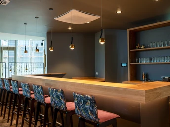 beleuchtete Bar mit Barhockern und Regal mit Gläsern