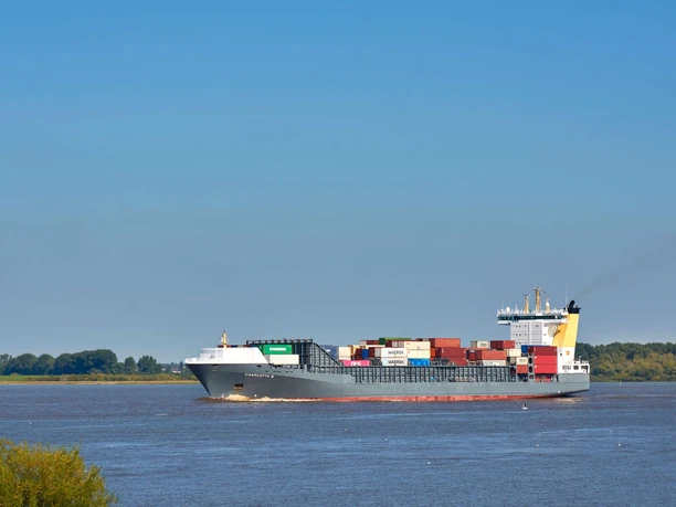 Containerschiff auf der Elbe Ein großes Containerschiff fährt auf der ruhigen Elbe entlang, umgeben von klarem blauem Himmel.