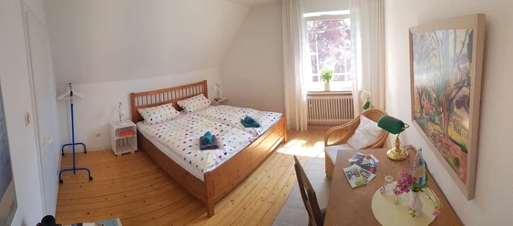 Maries B and B_Schlafraum Doppelzimmer _M Menke.jpg Zwei Einzelbetten mit bunter Bettwäsche in einem sonnigen, hellen Raum mit Holzboden und gemütlicher Einrichtung.