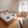 Maries B and B_Schlafraum Doppelzimmer _M Menke.jpg Zwei Einzelbetten mit bunter Bettwäsche in einem sonnigen, hellen Raum mit Holzboden und gemütlicher Einrichtung.