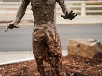 03_KSC_Collateral Sculptures_Thomas_Cyberfaun.jpg Skulptur eines menschenähnlichen Wesens mit Astgeweih, ausgestreckten Armen, stehend auf Mulch.Sculpture of a human-like creature with branch antlers, outstretched arms, standing on mulch.Socha člověku podobného tvora s parožím z větví, s roztaženýma rukama, stojícího na mulči.Rzeźba człekopodobnej istoty z porożem i wyciągniętymi ramionami, stojącej na ściółce.Sculptuur van een mensachtig wezen met een gewei van takken, uitgestrekte armen, staand op mulch.Scultura di una creatura umana con corna di ramo, braccia tese, in piedi su pacciame.