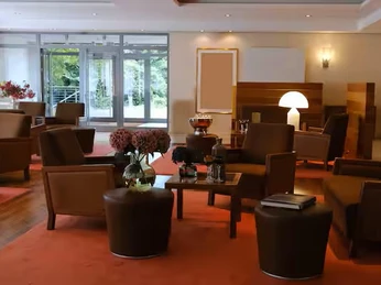 Bar im Ramada by Wyndham Düsseldorf Ratingen Elegante Hotelbar mit Ledersesseln und Tischlampen, durch Fenster Blick ins Grüne.