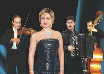 Italienische Nacht_M.Grandoni.jpg Eine Sängerin in einem festlichen, glitzernden Kleid steht vor einer Band, bestehend aus einem Violinisten, Akkordeonspieler und Kontrabassisten. Die Bandmitglieder tragen elegante schwarze und weiße Anzüge. Der Hintergrund ist stilvoll-dunkel, was den Fokus auf die Künstler lenkt.