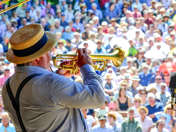 Dixielandfestival-Open-Air-Gala-1-©-Foto-Hendrik-Meyer.jpg Ein Musiker spielt Trompete vor einem großen, sommerlichen Open-Air-Publikum.