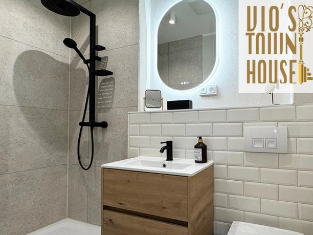 Modernes Badezimmer Modernes Bad mit kreisförmigem Spiegel, Dusche in Schwarz, Holzwaschtisch und hellem Fliesenboden.