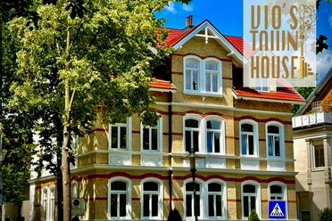 Außenansicht Historisches Stadthaus mit markanter Fassade, großen Fenstern und gepflegten Bäumen im Vordergrund.