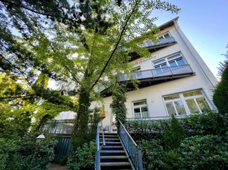 Foto Pension außen Drei-stöckiges Gebäude mit Balkonen, umgeben von Bäumen, Zugang über Treppen und Geländer.