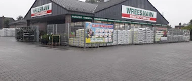 Wreesmann Sonderpostenmarkt.jpg Eingangsbereich des Wreesmann Sonderpostenmarkts mit Außenlager und Werbetafeln bei grauem Himmel.