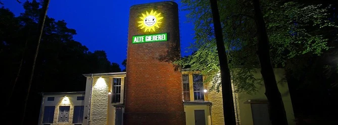 alte gießerei espelkamp.jpg Die Alte Gießerei in Espelkamp ist ein beleuchtetes Backsteingebäude mit einem strahlenden Sonnensymbol.