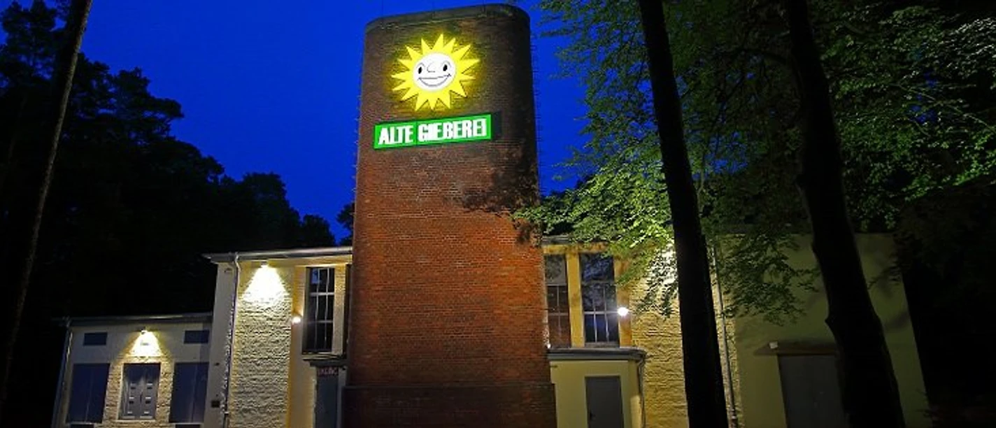 alte gießerei espelkamp.jpg Die Alte Gießerei in Espelkamp ist ein beleuchtetes Backsteingebäude mit einem strahlenden Sonnensymbol.
