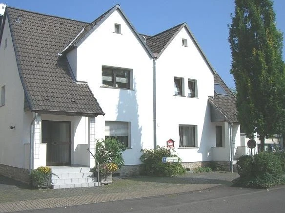 Ferienwohnung Kemper Zweistöckiges weißes Wohnhaus mit vier Giebeln, grauen Dächern und gepflegtem Vorgarten.