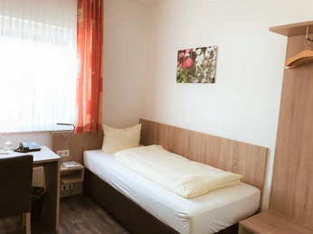 Herford-HotelPfennigskrug-Classic 2-H. Althoff.jpg Einzelzimmer mit Holzmöbeln, Einzelbett, Schreibtisch, heller Wandanstrich und Fotowanddekoration.