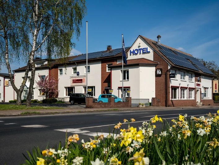 Außenansicht eines zweistöckigen Hotels mit weißer Fassade und dekorativen Backstein-Elementen.