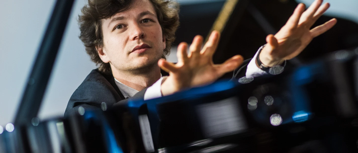 Mikhail Mordvinov Pianist Mikhail Mordvinov am Flügel mit erhobenen Händen.