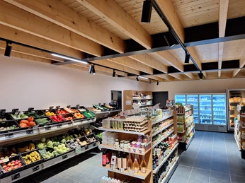 Biolandhof Freese_Gemeinde Rhauderfehn_Innansicht_neuer Laden_Januar 2520241214_081432.jpg Innenansicht eines kleinen Supermarkts mit Holzdecke, Gemüseregalen links und Regalen mit verschiedenen Lebensmitteln in der Mitte