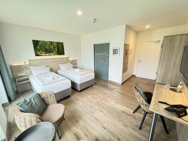 Weinhaus Zimmer Helles Hotelzimmer mit zwei Einzelbetten, moderner Einrichtung, Schreibtisch und Sitzbereich.