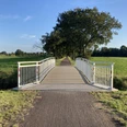 Weiße Brücke am Ostfriesland Wanderweg, Gemeinde Rhauderfehn, Ostfriesland Schmale Brücke mit weißen Geländern über einen Graben, führt zu einem von Bäumen gesäumten Weg in einer grünen Wiesenlandschaft.