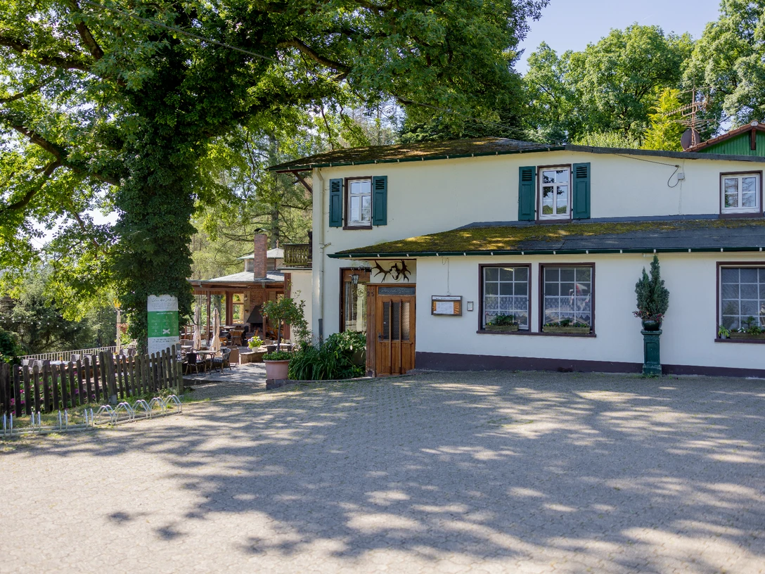 Bergische Schweiz Zweistöckiges weißes Gasthaus im Grünen, umgeben von Bäumen. Elegante Terrasse im Hintergrund.