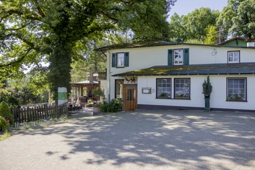 Bergische Schweiz Ein einladendes Landgasthaus umgeben von üppigen, grünen Bäumen und einem sonnigen Außenbereich.