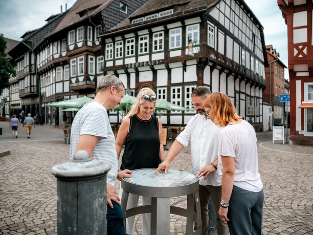Vier mensen kijken naar een vat op het bierpad op het marktplein van Einbeck.