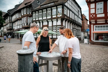 Einbecker Bierpfad Vier Personen betrachten ein Fass des Bierpfades auf dem Einbecker Marktplatz.