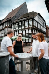 Vier mensen staan rond een vat op het Einbeck Bierpad en kijken ernaar.
