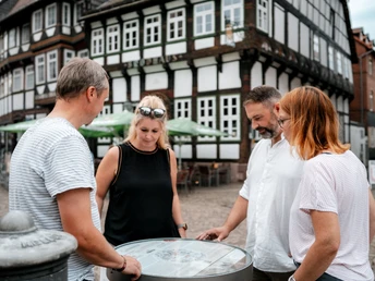 Vier Personen stehen um ein Fass des Einbecker Bierpfades und schauen sich dieses an.