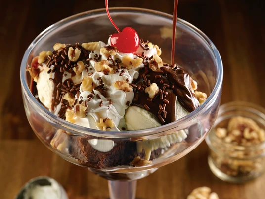 HRC Hot Fudge Brownie 6.jpeg Dessert im Cocktailglas, Schokosoße wird aus einer kleinen Sauciere auf das Dessert gegossenDessert in a cocktail glass, chocolate sauce is poured onto the dessert from a small sauce boat