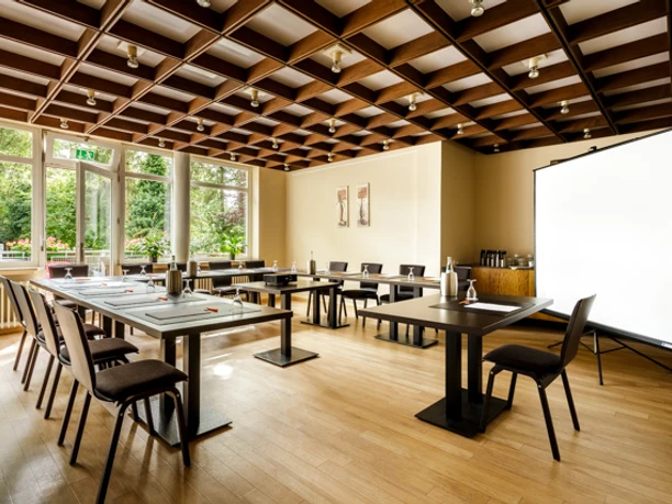 Raum mit Blick ins Grüne Conference room with U-shaped seating, screen and view of nature
