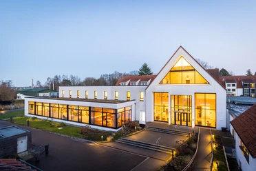 HolsingVital - Außenansicht erleuchtet Außenansicht der Reha-Klinik HolsingVital bei leichter Dämmerung, das Haus ist von innen beleuchtet
