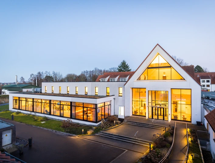 HolsingVital - Außenansicht erleuchtet Außenansicht der Reha-Klinik HolsingVital bei leichter Dämmerung, das Haus ist von innen beleuchtet