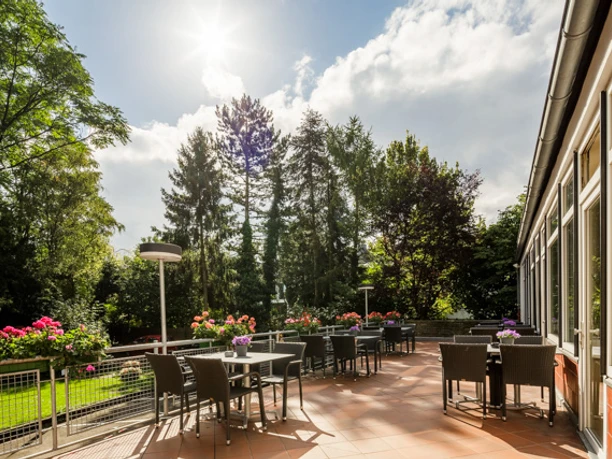 Terrace with a view of green trees, furnished with tables and chairs