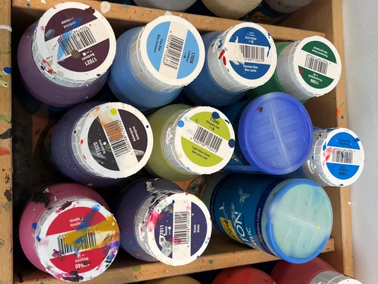 Atelier Verschiedenfarbige Acrylfarbflaschen stehen dicht nebeneinander in einem Holzregal im Künstleratelier.