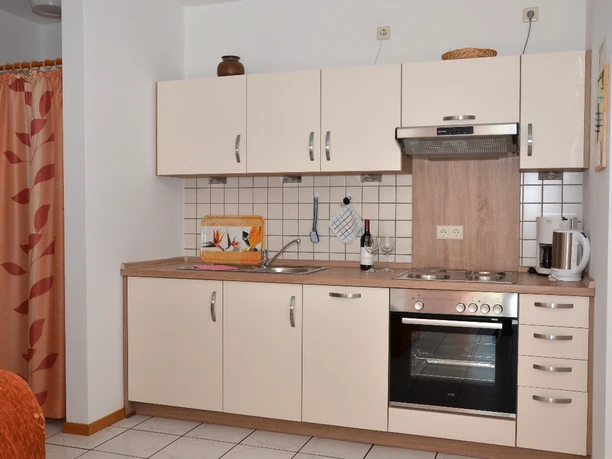 Küche Hühnerhof Helle Küchenzeile mit cremefarbenen Schränken, Herd, Backofen, Spüle und Kaffeemaschine.