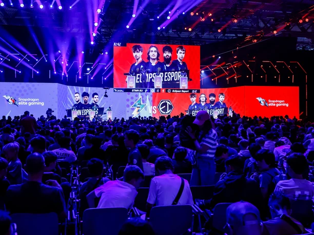 gamescom Large crowd at an e-sports event with colorful stage lighting and impressive screens.