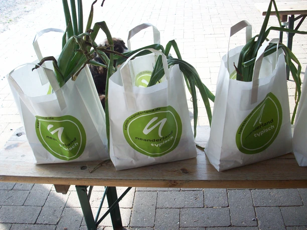 Gemüse im Verkauf von Gut Hixholz Frisch geerntete Gemüse in Taschen mit dem Logo "neanderland typisch" auf einem Holztisch arrangiert.